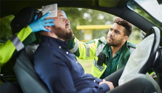 man in car accident getting treated by medical personnel